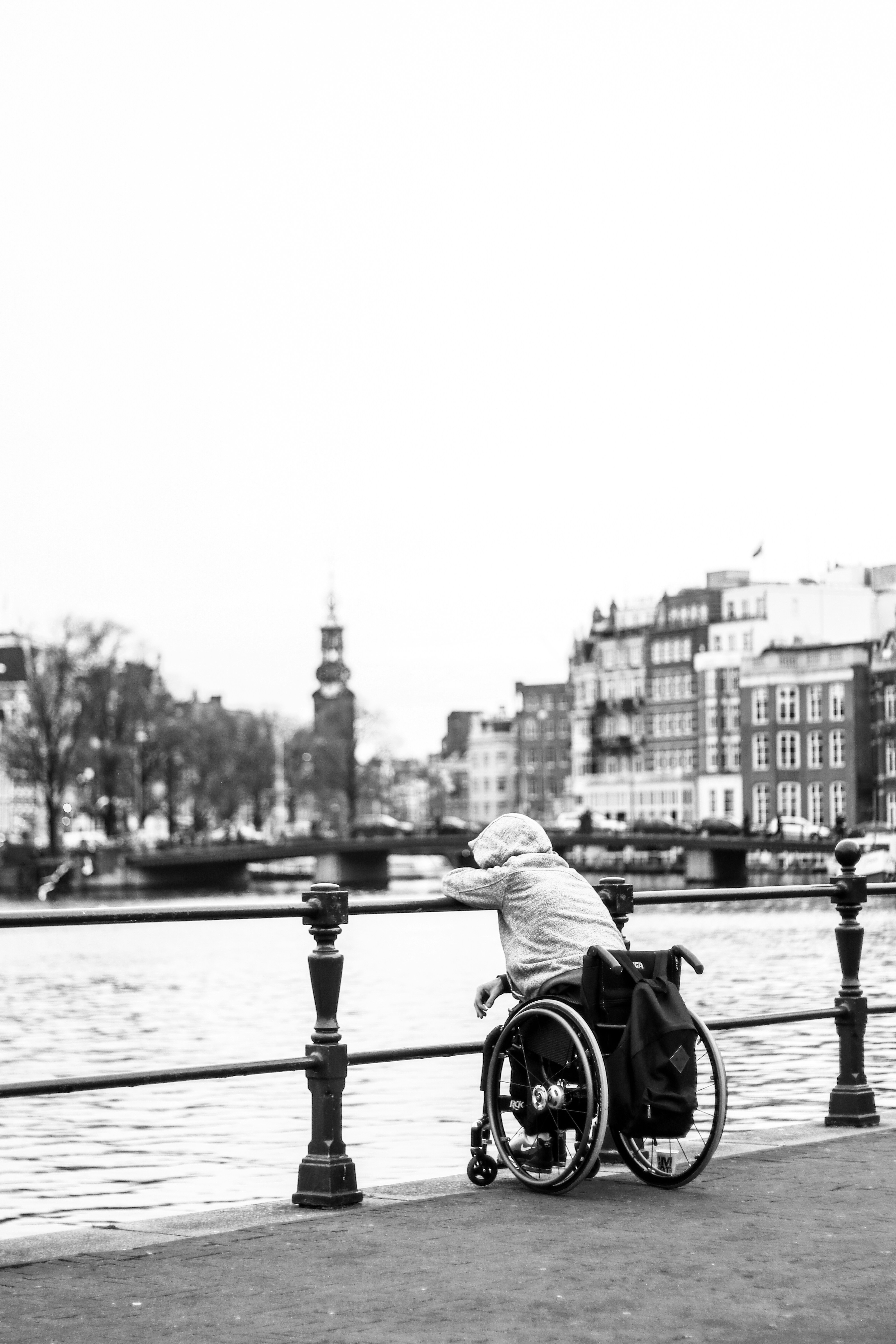 Wheelchair user alone beside a canal in a city setting