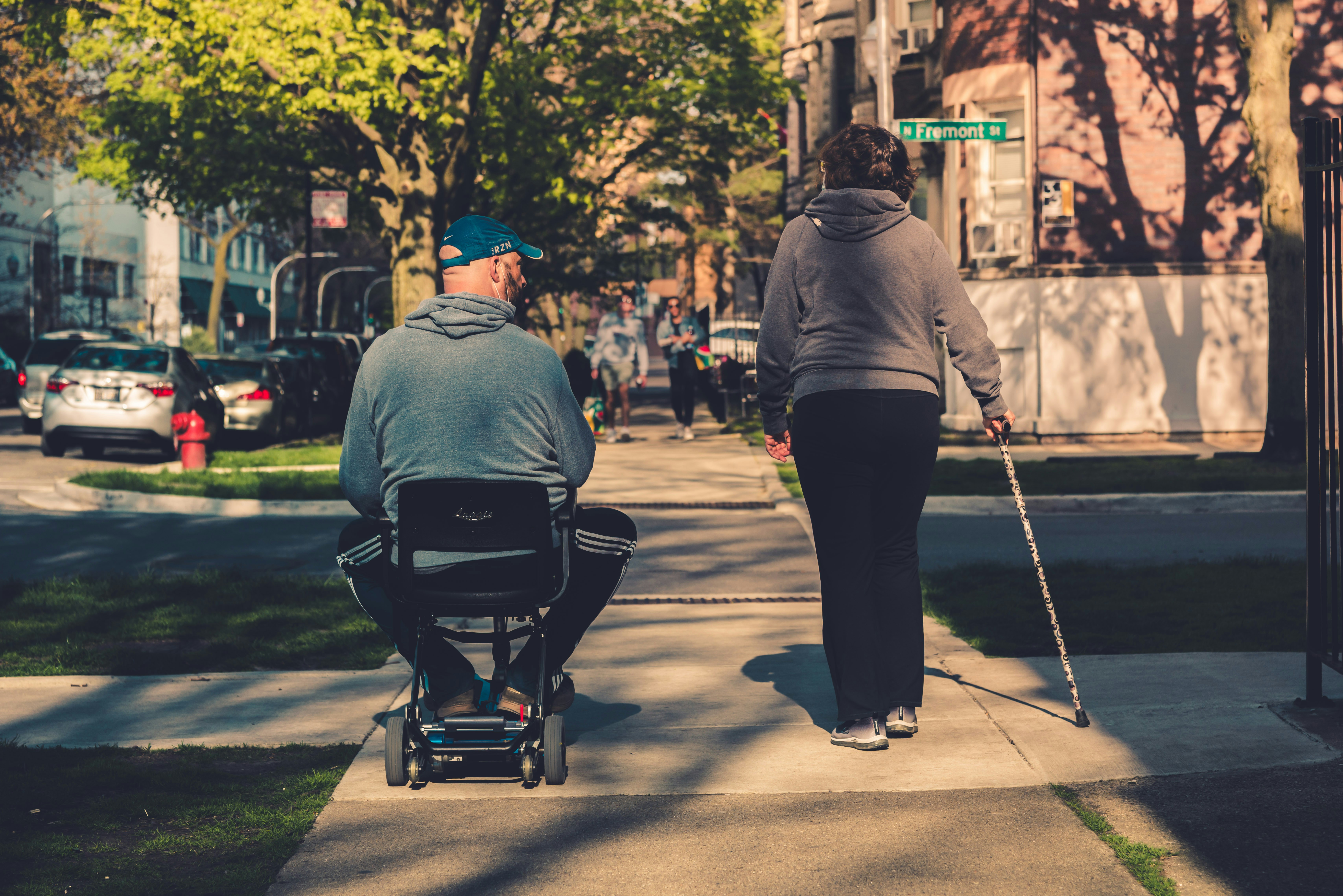 Two mobility aid users moving through an urban neighborhood