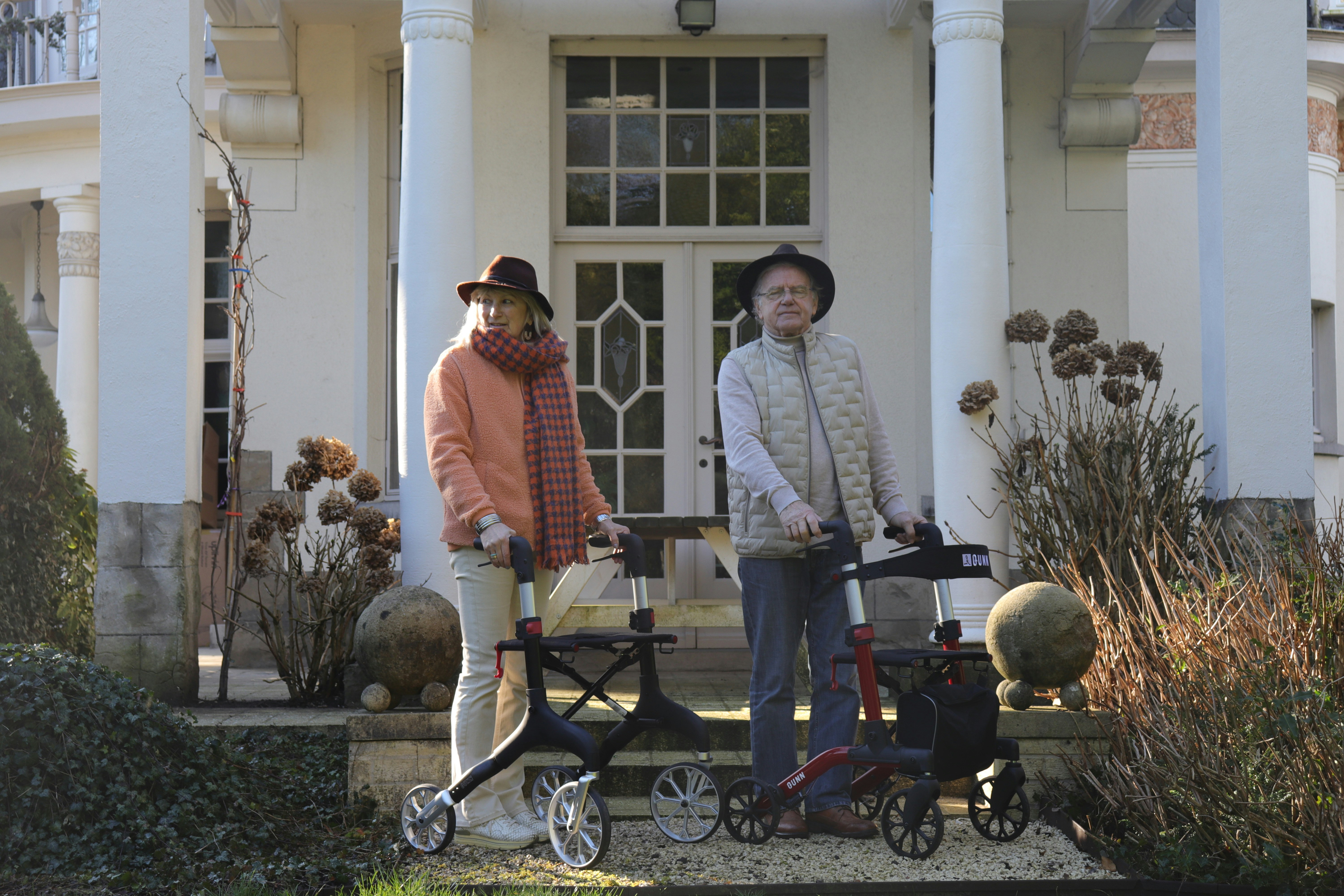 Two people standing with rollators in front of a home entrance