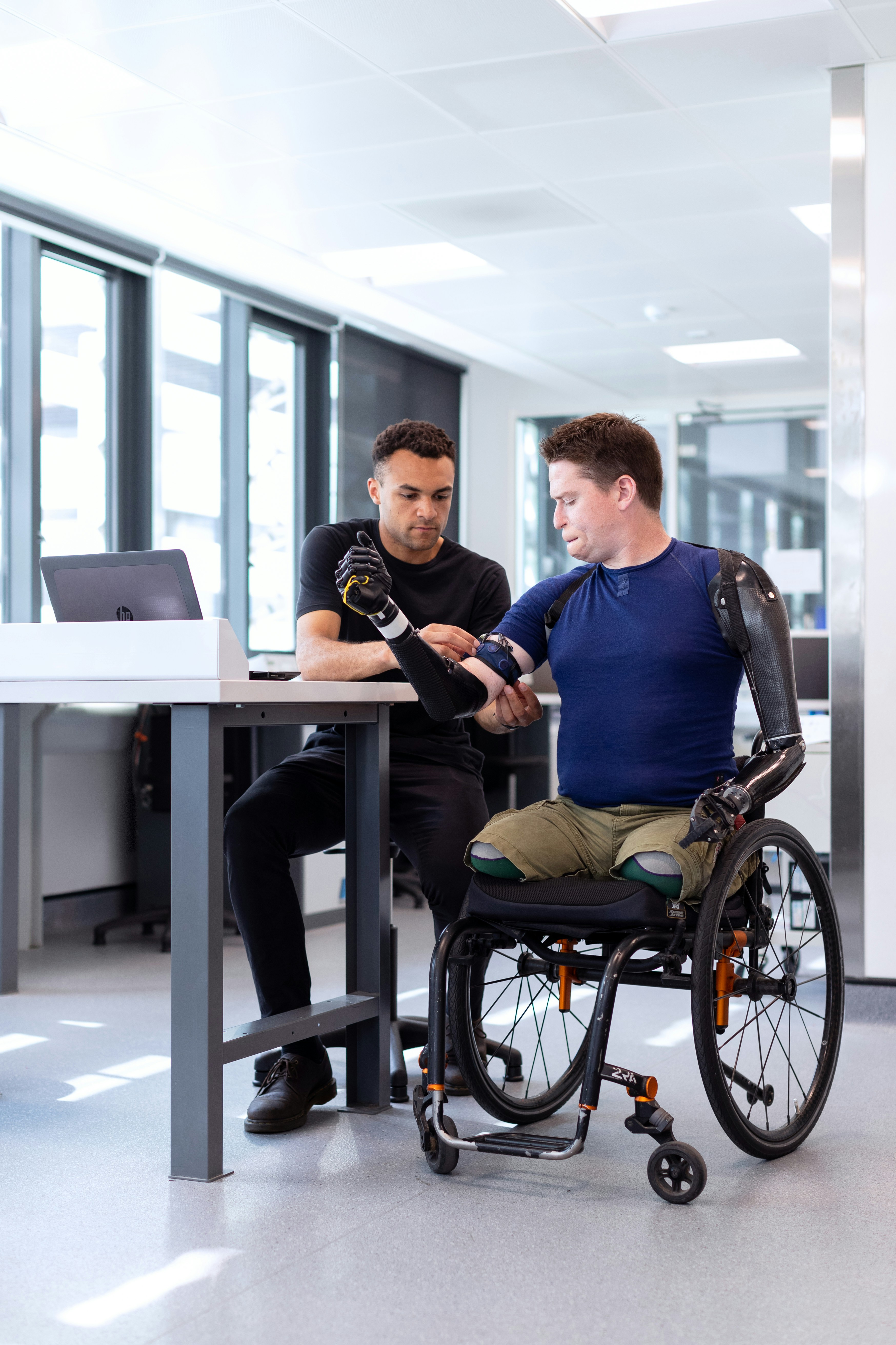 Clinician adjusting an assistive prosthetic device with a wheelchair user