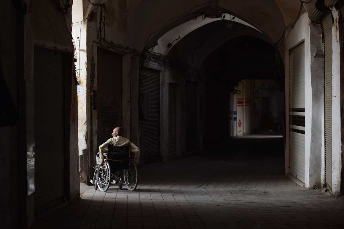 A person in a wheelchair looks down a dark hallway.