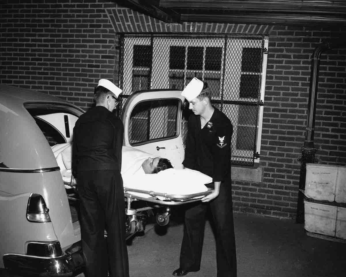 Two medics load patient onto stretcher from ambulance.