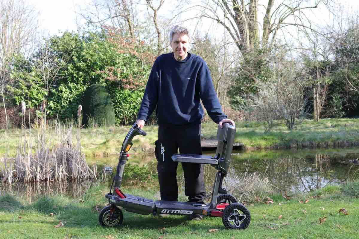 Man standing with mobility scooter by water